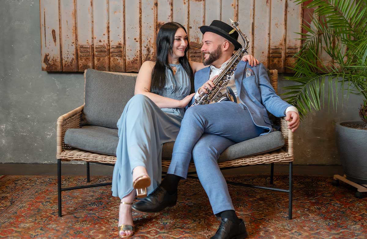 Musikerpaar auf Sofa mit Saxophon – Live Musik für Euer Event mit Gefühl und Vertrautheit